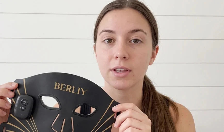 Megan holding a black BERLIY LED face and neck mask in the customer review section.